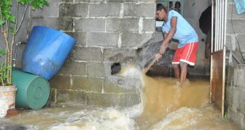 Cet homme a été obligé de détruire les murs de sa cour pour évacuer l'eau lors des pluies diluviennes en mars 2015. Photo: Beekash Roopun