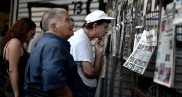 Des grecs lisent les journaux dans un kiosque du centre d'Athènes, le 31 juillet 2015. [Photo: AFP]