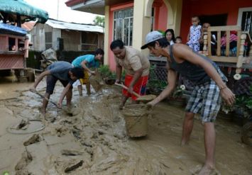 AFP/AFP - Les habitants enlèvent la boue le 20 octobre 2015 dans les rues de Cabanatuan City, au nord de Manille, apportée par les fortes pluies occasionnées par le typhon Koppu qui a fait au moins 22 morts  