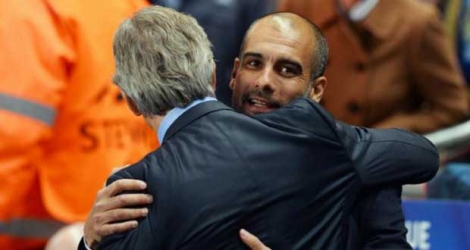 Manuel Pellegrini (g), entraîneur de Manchester City, donnant l'accolade à Pep Guardiola, l'entraîneur du Bayern Munich, qui succédera au Chilien sur le banc des Citizens à la fin de la saison, le 2 octobre 2013 à Manchester.