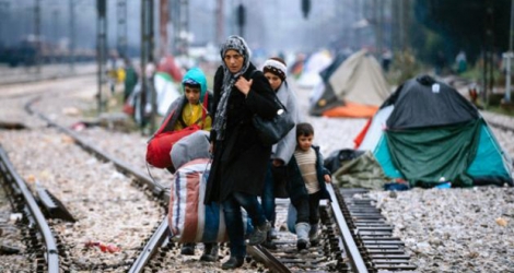 Une femme et trois enfants marchent sur des rails reliant la Grèce à l'Europe de l'ouest, à la frontière gréco-macédonienne près du village grec d'Idomeni, le 9 mars 2016.