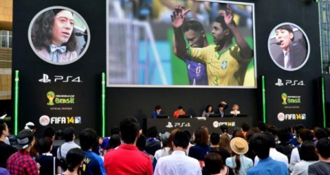 Des fans assistent, sur un écran géant, à un match de foot sur PlayStation à Tokyo.