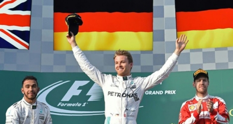 L'Allemand Nico Rosberg (Mercedes) bras levés sur le podium, fête sa victoire au GP d'Australie devant son coéquipier Lewis Hamilton (g) et Sebastian Vettel (Ferrari), le 20 mars 2016 à Melbourne.