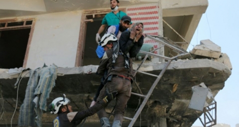 Des bénévoles du service de défense civil syrien évacuent des habitants d'un immeuble détruit par des bombardements, dans un quartier rebelle d'Alep le 23 avril 2016.