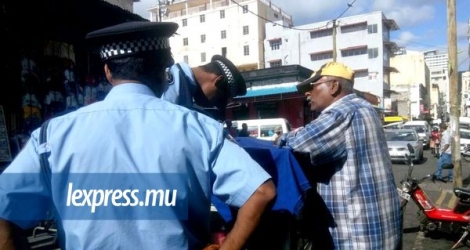 Un policier dressant une contravention à un marchand ambulant à la rue Farquhar, Port-Louis, mardi 24 mai.
