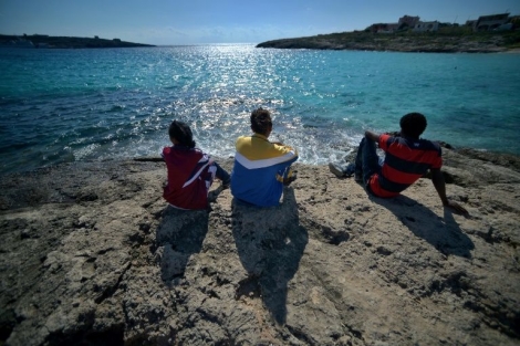 De jeunes migrants regardent la mer depuis l'île de Lampedusa.