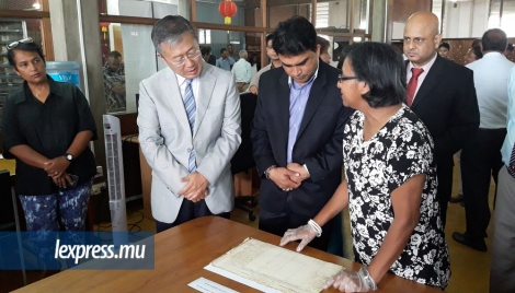 Une employée des Archives montre un document ancien au ministre Dan Baboo et à l’ambassadeur de Chine Li Li.