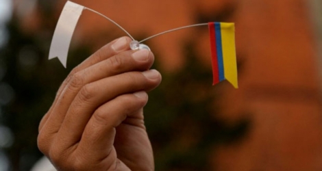 Un drapeau blanc pour la paix et un drapeau colombien tenus dans une main à Bogota par un manifestant après l'annonce d'un nouvel accord de paix, le 15 novembre.