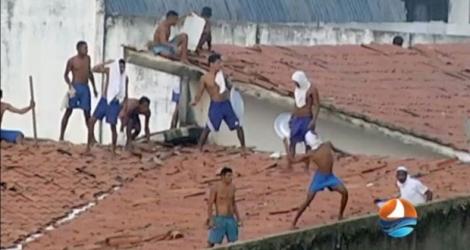 Une capture d'écran de la télévision Ponta Negra prise le 14 janvier 2017 du centre pénitentiaire d'Alcaçuz près de Natal, état du Rio Grande do Norte, dans le nord-est du Brésil, montre des détenus jetant des objets du toit de la prison pendant une émeute.