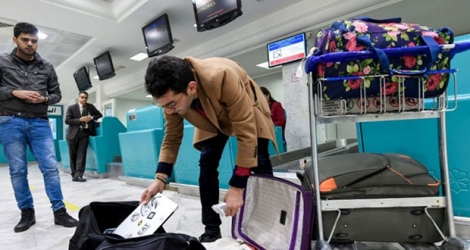 Un voyageur met son ordinateur dans son sac avant de s'envoler pour Londres à l'aéroport de Tunis le 25 mars 2017 