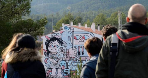 Des visiteurs devant l'une des oeuvres de street art qui ornent les murs du village de Fanzara.