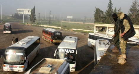 Des combattants de l'opposition observent des bus évacuant des civils de la ville rebelle d'Al-Rashideen, à l'est d'Alep, le 14 avril 2017 en Syrie .