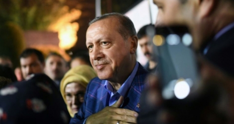 Le président Erdogan (c), accompagné de sa femme Emine, salue ses supporters en sortant du siège du parti AKP, le 16 avril 2017 à Istanbul.