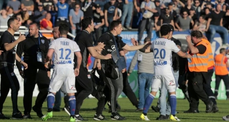 Les joueurs de Lyon Rafael da Silva (d) et Jordan Ferri (g) sont protégés par le staff lyonnais lors des échauffourées à la mi-temps du match contre Bastia, le 16 avril 2017 à Furiani.
