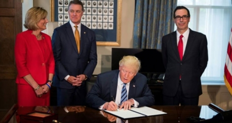 Donald Trump signe des documents demandant la révision de certaines dispositions financières, entouré, notamment, du secrétaire au Trésor Steven Mnuchin (D), à Washington le 21 avril 2017.