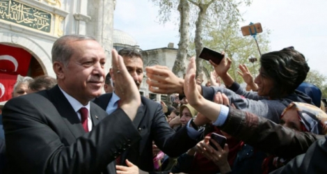 Le président turc Recep Tayyip Erdogan (g) salue ses supporteurs au lendemain de sa victoire au référendum sur le renforcement de ses pouvoirs, le 17 avril 2017 à Istanbul.