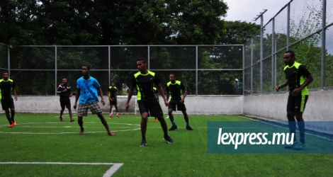 Vêtus de maillots vert et noir, les jeunes footballeurs courent et driblent avec le ballon.