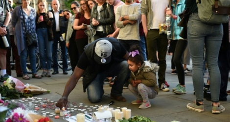 Un homme et sa petite fille allument des bougies à quelques pas du lieu de l'attentat à l'Albert Square de Manchester le 23 mai 2017 .