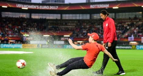 Un jeune volontaire de l'Euro glisse dans une flaque d'eau sous les yeux de la sélectionneuse de l'équipe d'Allemagne Steffi Jones, avant Allemagne-Danemark, à Rotterdam le 29 juillet 2017.