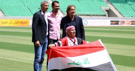 Les anciens footballeurs argentin Hernan Crespo (g), irakien Younis Mahmoud (c) et espagnol Michel Salgado (d) posent avec le drapeau irakien au stade de Bassora, le 14 août 2017 .