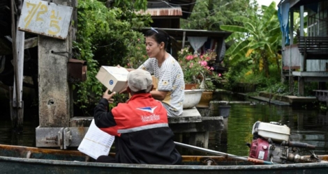 Nopadol, postier, distribue des lettres et colis aux habitants vivant sur les bords d'un canal dans la province de Bang Khun Thian, près de Bangkok en Thaïlande, le 17 juillet 2017 .