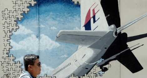 Photo d'archives prise le 8 mars 2016 montrant un homme à Shah Alam en Malaisie marchant devant une fresque murale de l'avion disparu du vol MH370 de Malaysia Airlines.