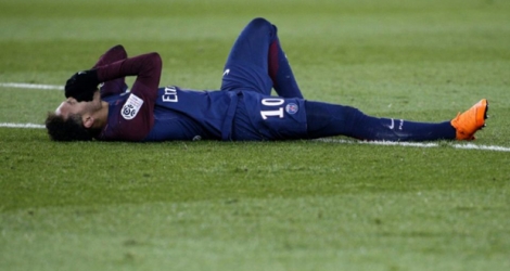 La star du PSG Neymar au sol après s'être blessé à la cheville droite contre Marseille en Ligue 1, le 25 février 2018 au Parc des Princes 