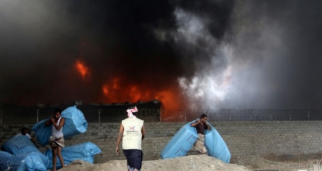 Des travailleurs tentent de sauver des flammes des sacs d'aide alimentaire dans un dépôt du Programme alimentaire mondial (PAM) dans le port yéménite de Hodeida, sur la mer Rouge, le 31 mars 2018 