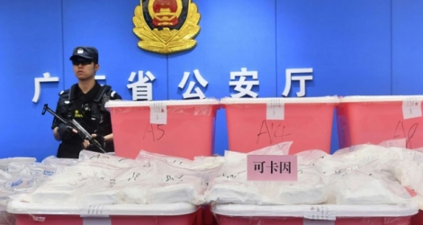 Un policier chinois monte la garde le 24 avril 2018 près de sacs de cocaïne saisis à Guangzhou dans la province méridionale du Guangdong 