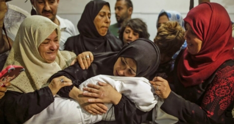 La mère de Leila al-Ghandour (C), un bébé palestinien de huit mois mort lundi après avoir inhalé des gaz lacrymogènes tirés par l'armée israélienne selon le ministère de la Santé à Gaza, tient le corps de son enfant à l'hôpital al-Shifa de Gaza, le 15 mai 2018 