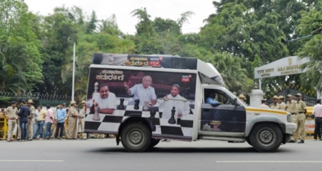 Un véhicule arborant une affiche illustrant la partie d'échecs politique en cours au Karnataka passe devant la résidence du gouverneur de l'Etat à Bangalore en Inde le 16 mai 2018.