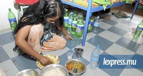 Une Bangladaise prenant son repas à même le sol, dans le dortoir d’une usine textile.