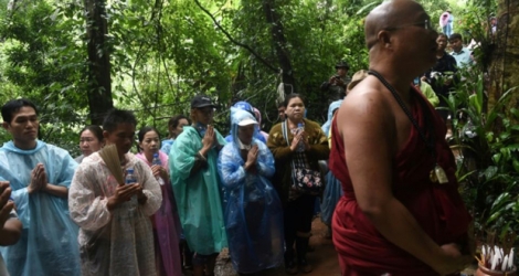 Un moine bouddhiste et des familles des enfants coincés dans une grotte prient à Chiang Rai, le 27 juin 2018.