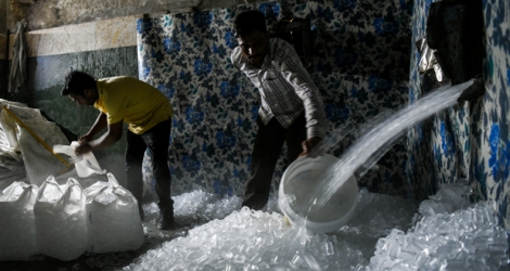 Le jeune ouvrier indien projette le lourd parpaing de glace sur le plancher vermoulu de la plateforme.
