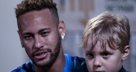 Neymar, avec son fils Davi Lucca, accorde un entretien à l'AFP, le 21 juillet 2018 à Praia Grande, près de Sao Paulo.