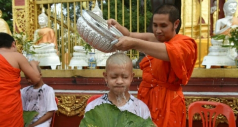 Un moine bouddhiste nettoie le crâne rasé d'un des enfants secourus, dans un temple bouddhiste de Mae Sai, au nord de la Thaïlande.