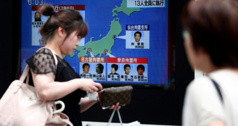 Des piétons passent devant un écran de télévision diffusant des informations sur l'exécution de six membres de la secte Aum Vérité Suprême, le 26 juillet 2018 à Tokyo