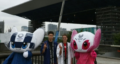 Les nageurs japonais Kosuke Hagino (2g) et canadienne Kylie Masse (3g) posent avec les mascottes des JO de Tokyo devant le centre aquatique olympique, le 7 août 2018 à Tokyo.