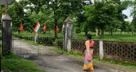 Une ouvrière du thé indienne devant l'entrée à une plantation fermée à Siliguri, dans l'est de l'Inde en raison de la grève, le 7 août 2018 