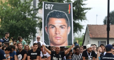 Portrait de Cristiano Ronaldo brandi par des supporters de la Juventus, lors de son arrivée au centre médical du club, le 16 juillet 2018 à Turin 