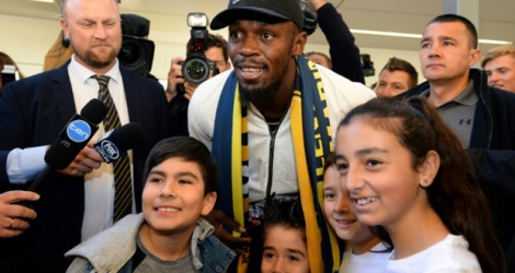 Usain Bolt pose avec de jeunes fans à son arrivée à l'aéroport de Sydney, samedi 18 août 2018. 