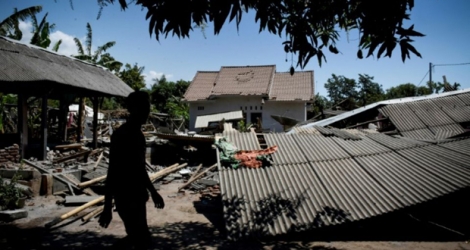 Un homme marche près d'un bâtiment effondré dans le village de Sugian sur l'île indonésienne de Lombok secouée par une série de séismes, le 20 août 2018 