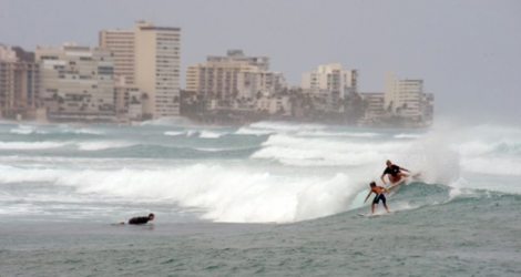 Des surfers profitent des vagues exceptionnelles apportées par l'ouragan Lane, sur la plage de Waikiki, à Hawaï, le 24 août 2018.