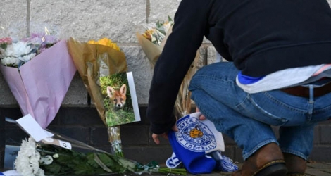 Un supporter dépose des fleurs et une écharpe du club de football de Leicester devant le stade de cette ville du centre de l'Angleterre, le 28 octobre 2018. Un hélicoptère du président du club, le Thaïlandais Vichai Srivaddhanaprabha, s'est écrasé et on est sans nouvelles de l'homme d'affaires. 