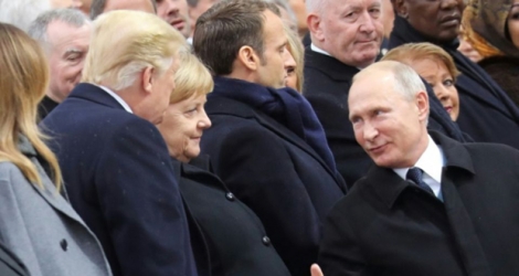 Le président russe Vladimir Poutine s'entretient avec son homologue américain Donal Trump, devant la chancelière allemande Angela Merkel, le 11 novembre 2018 à Paris.