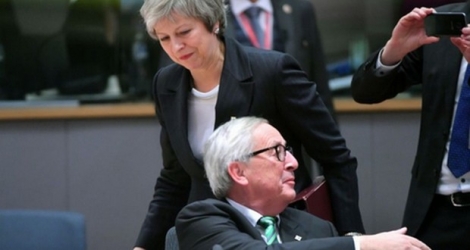 La Première ministre britannique Theresa May passe derrière le président de la Commission européenne Jean-Claude Juncker au sommet européen de Bruxelles, où elle est venue chercher de l'aide pour faire passer l'accord de Brexit, le 13 décembre 2018 