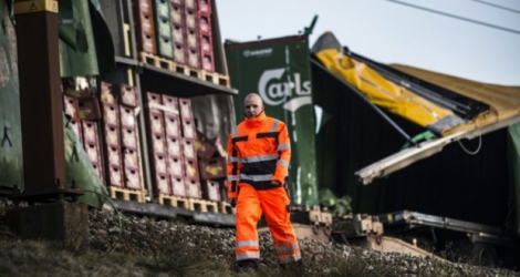 Un employé des chemins de fer passe devant les wagons endommagés d'un train de marchandises sur le pont du Grand Belt au Danemark après un accident meurtrier, le 2 janvir 2019.