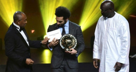 Mohamed Salah reçoit le trophée du Ballon d'Or africain 2018 des mains du président de la CAF Ahmad Ahmad, sous le regard du président George Weah à Dakar, le 8 janvier 2019.