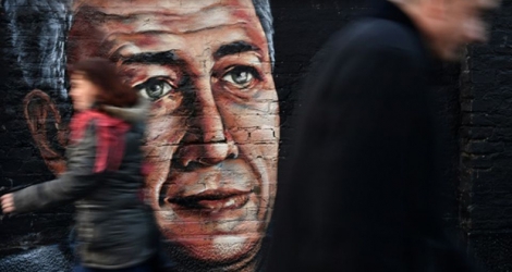 Des passants marchent à Belgrade le 14 janvier 2019 devant une fresque murale avec le portrait d'Oliver Ivanovic, homme politique serbe du Kosovo assassiné l'année précédente
