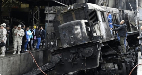 Des membres des forces de sécurité et des passants se tiennent sur un quai en gare du Caire après un accident de train ayant provoqué un incendie le 27 février 2019.